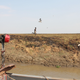 A South Sudanese boy on the South Sudanese riverside tries to keep up with a boat that evacuates refugees.